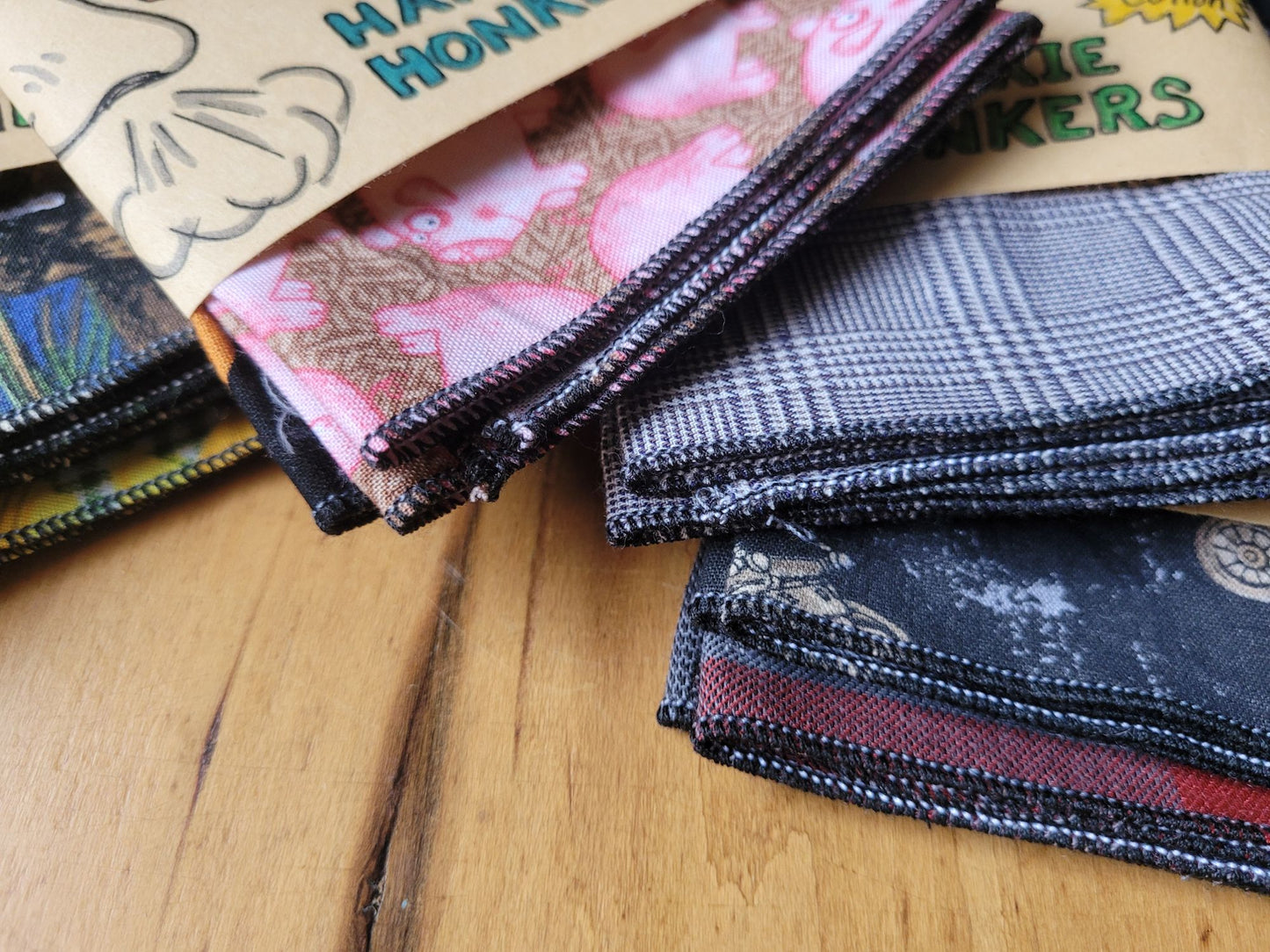Stack of patterned fabric hankies showing a close up of the rolled hem, on a wooden surface