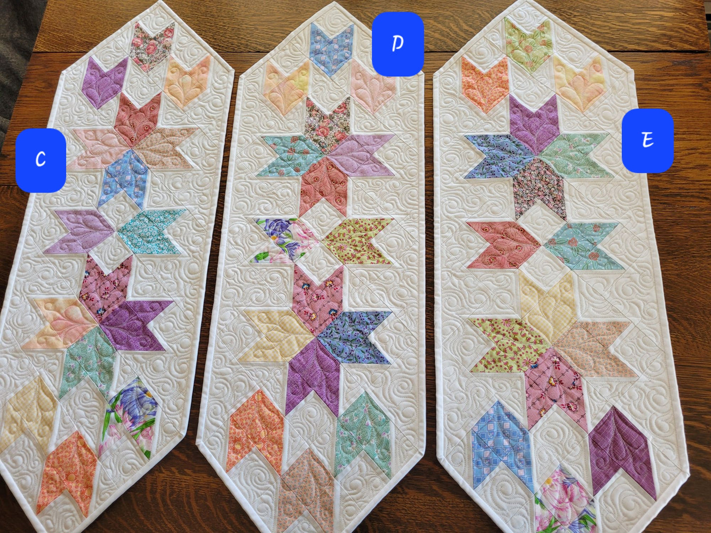 Spring tulip table runner in pastel patchwork on white background. Three runners shown with variations in color placement. Labeled C, D and E for choosing a checkout.