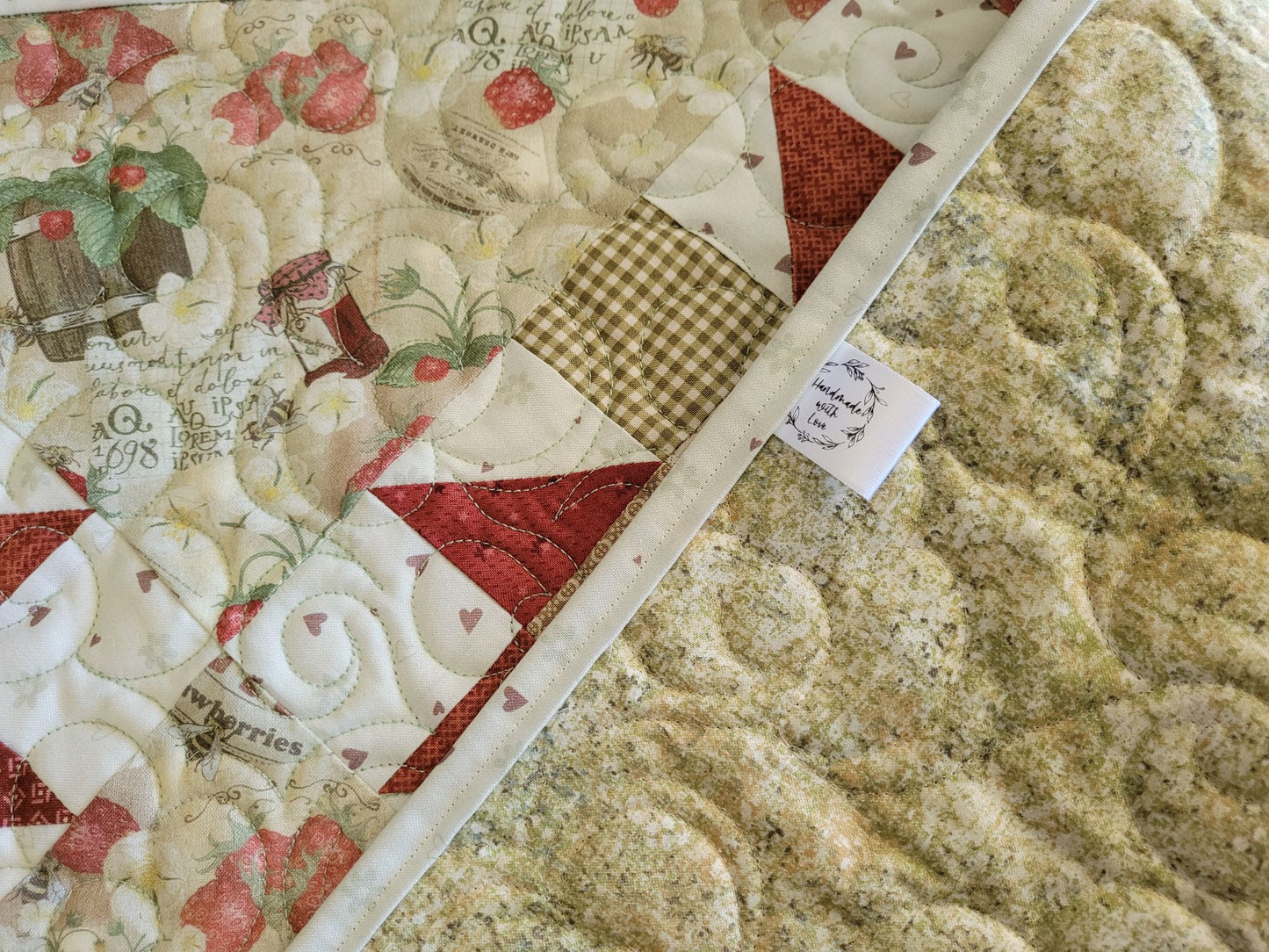 strawberry quilted table runner, folded to show backing and handmade tag