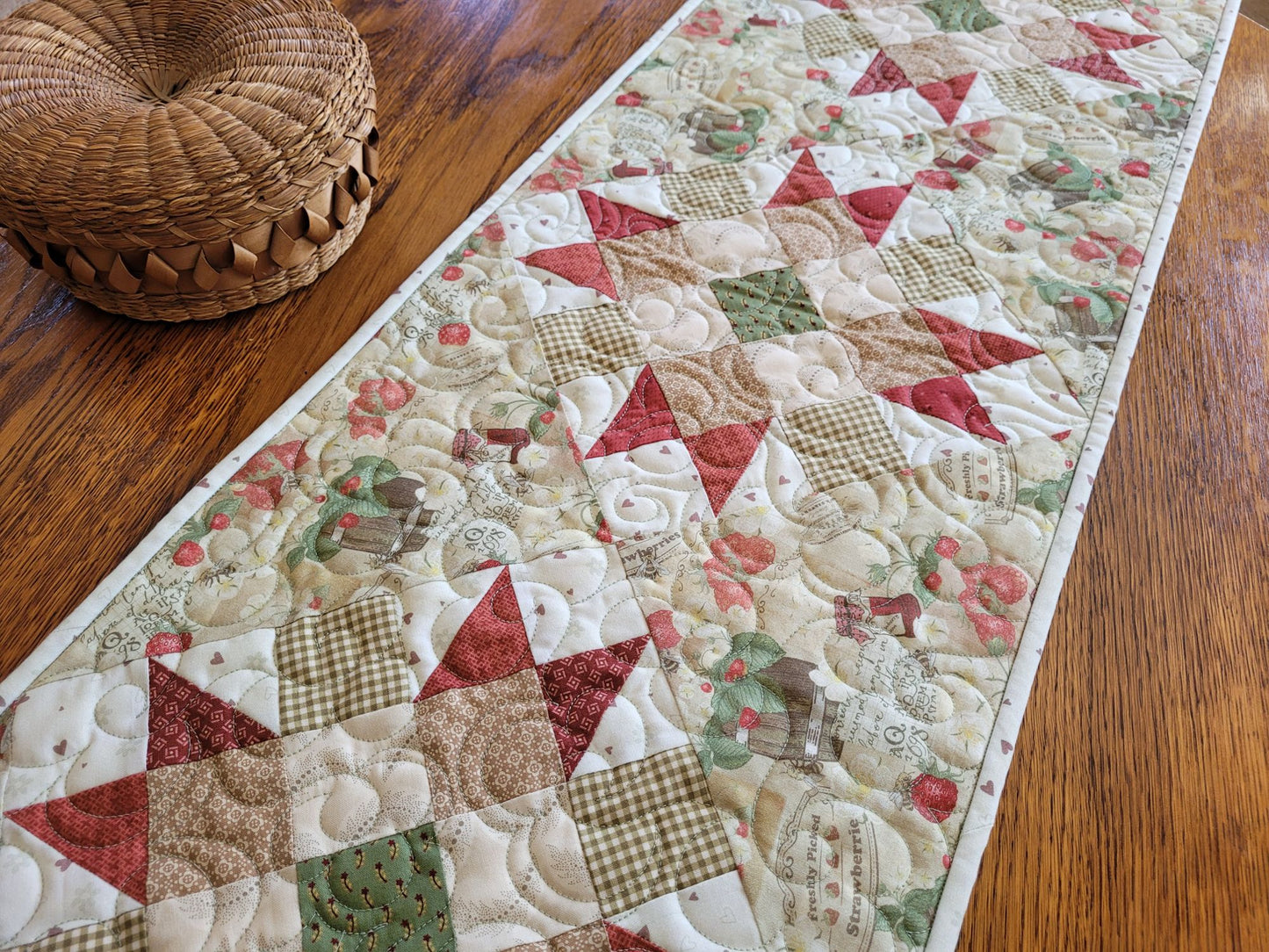 Strawberry quilted table runner on table with small wicker basket beside