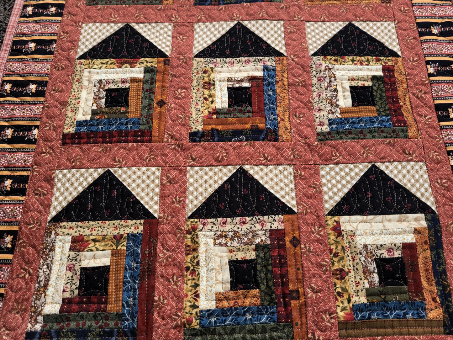 Quilt with house pattern featuring various colors and textures