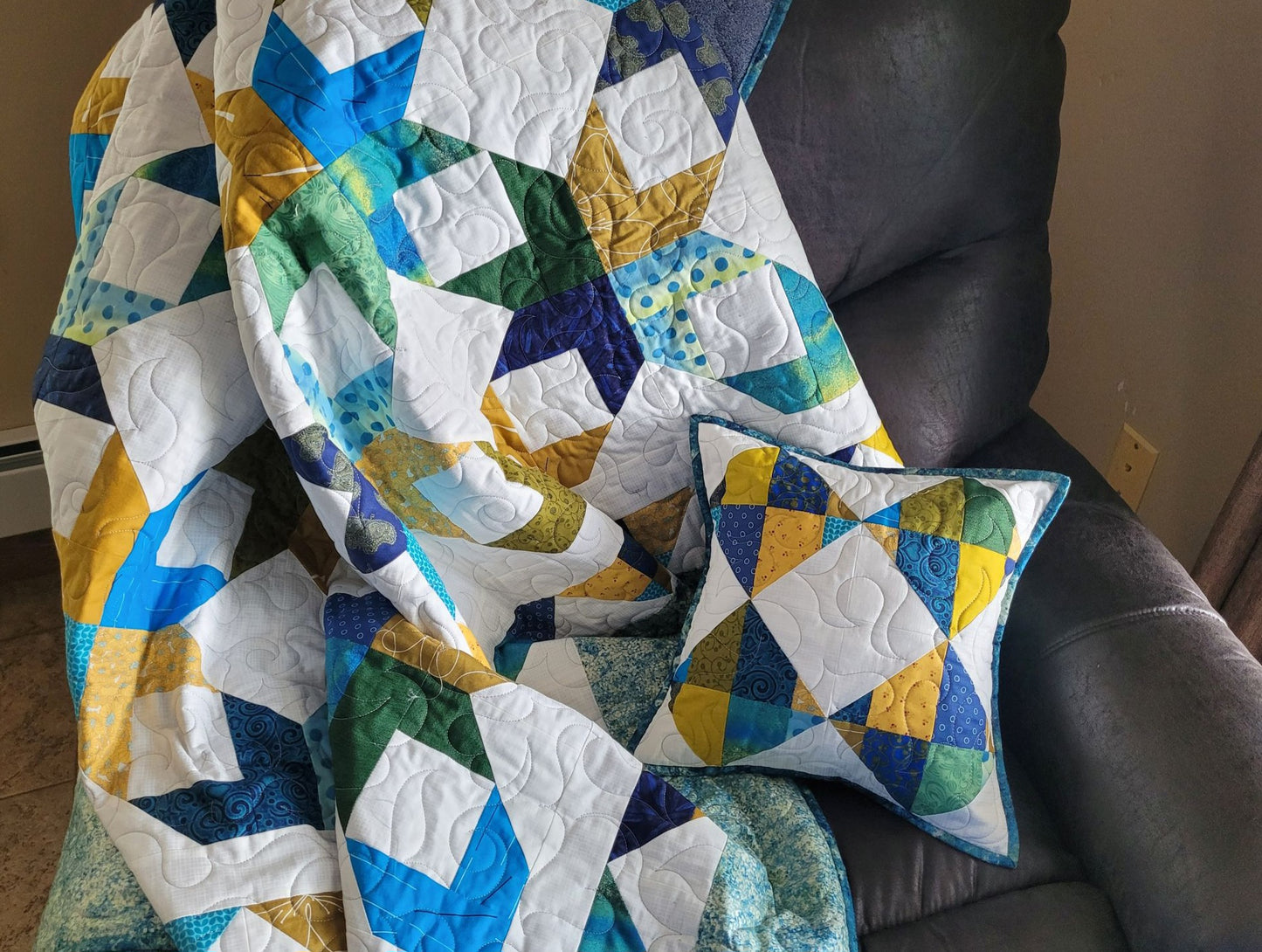 Throw quilt and pillow shown indoors on a lazyboy chair.