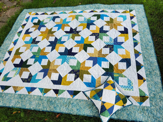 Scrappy star throw quilt with matching pillow, done in tones of blue, gold and green.