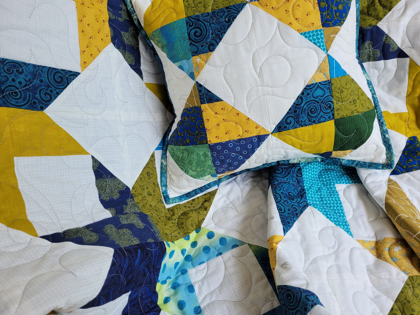 Close up detail of quilted throw blanket and pillow.