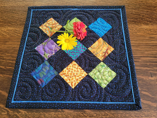Colorful quilted square with floral patterns on a wooden surface
