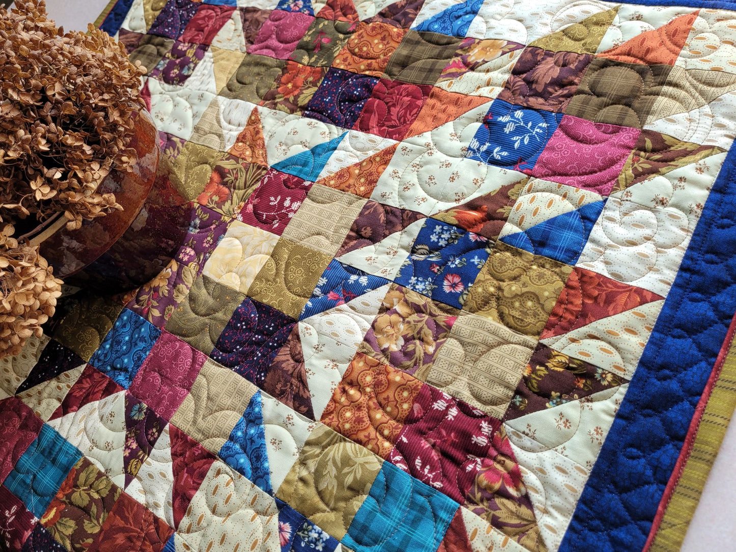 Colourful quilt with patchwork design featuring various patterns and colours.
