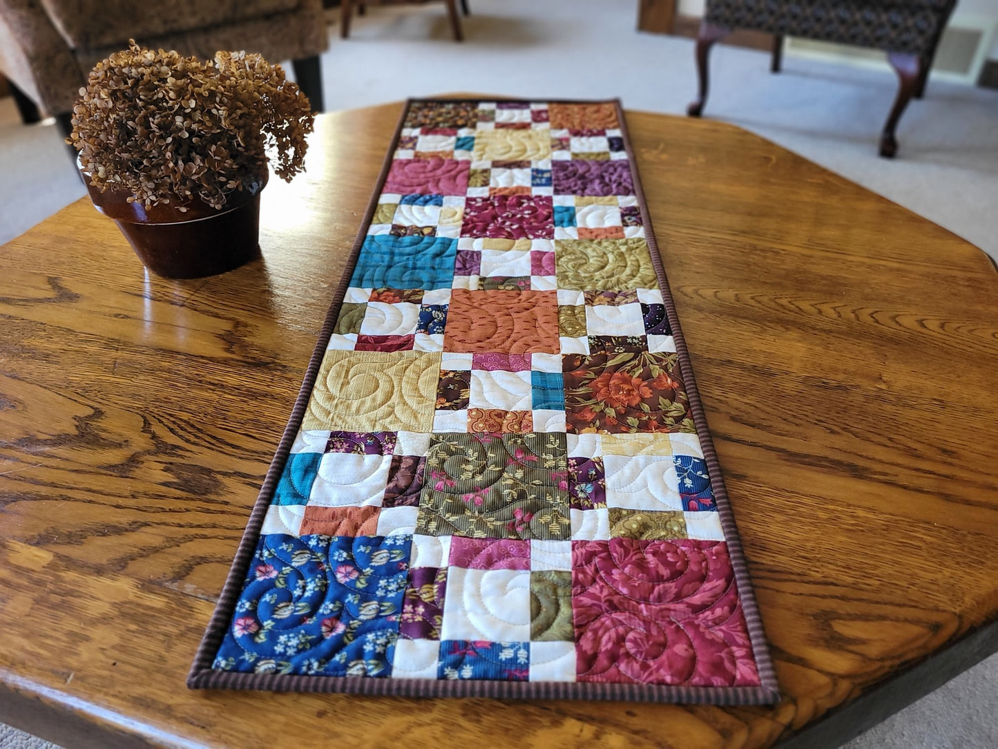 Quilted table runner on a wooden table with a plant in the background