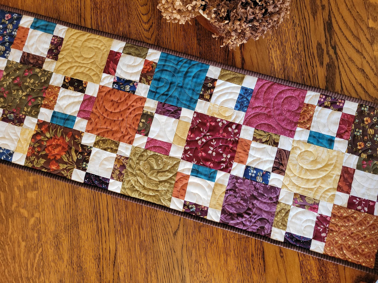 Colourful quilted table runner on a wooden surface