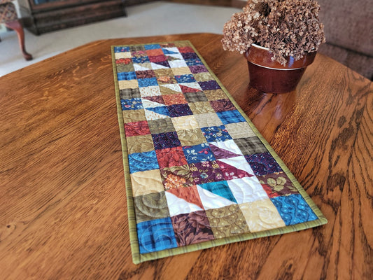 Colourful patchwork table runner on a wooden table with a blurred indoor background