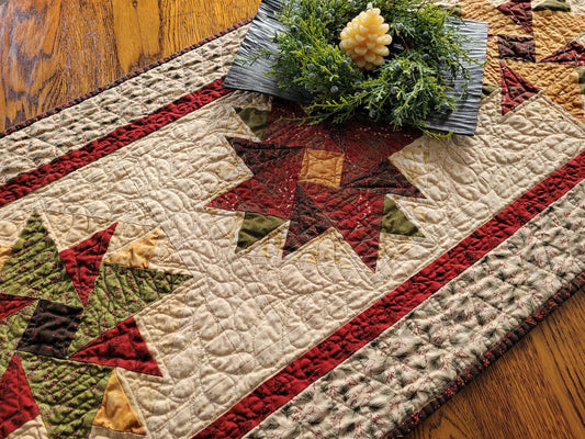 Quilted table runner with star patterns on a wooden surface with a candle