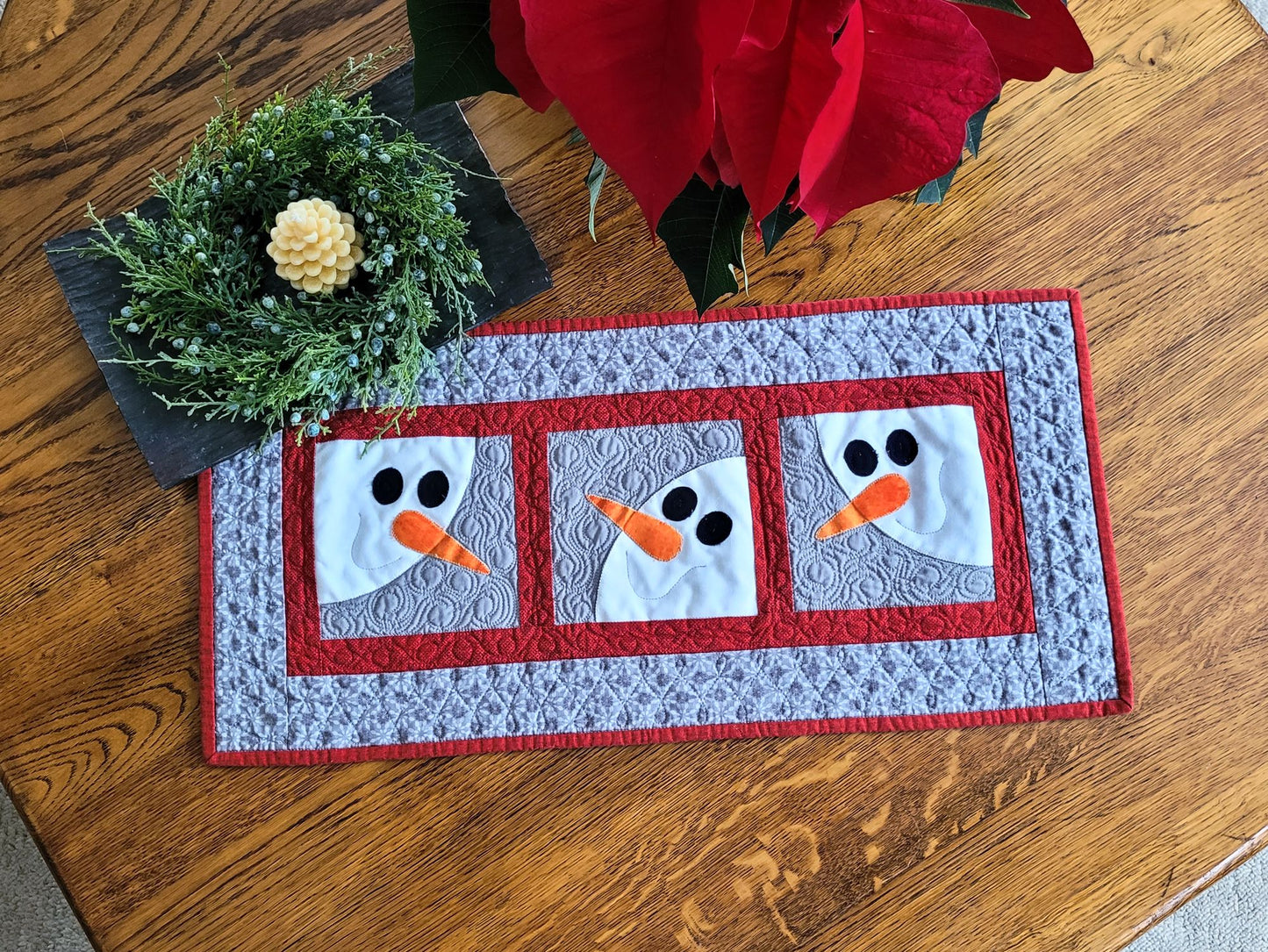 Quilted table runner with snowman design on a wooden surface