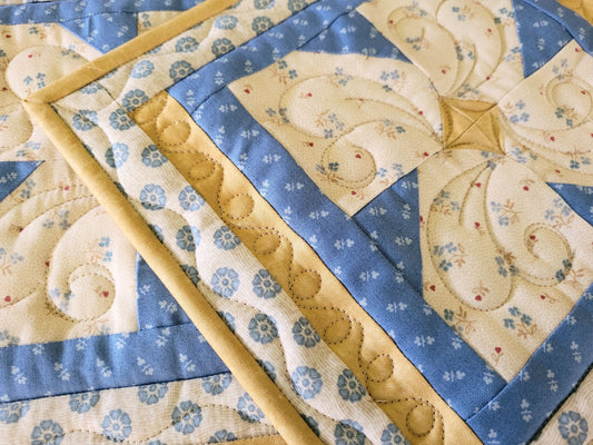 Close up of quilted flower hot mats showing quilted texture and blue and beige fabric detail.