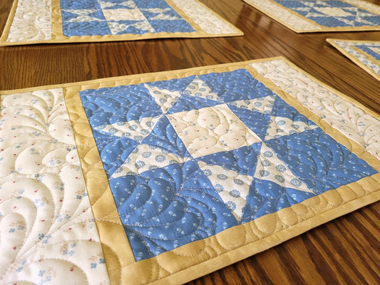 Quilted star placemats with blue and beige fabrics on a wooden surface