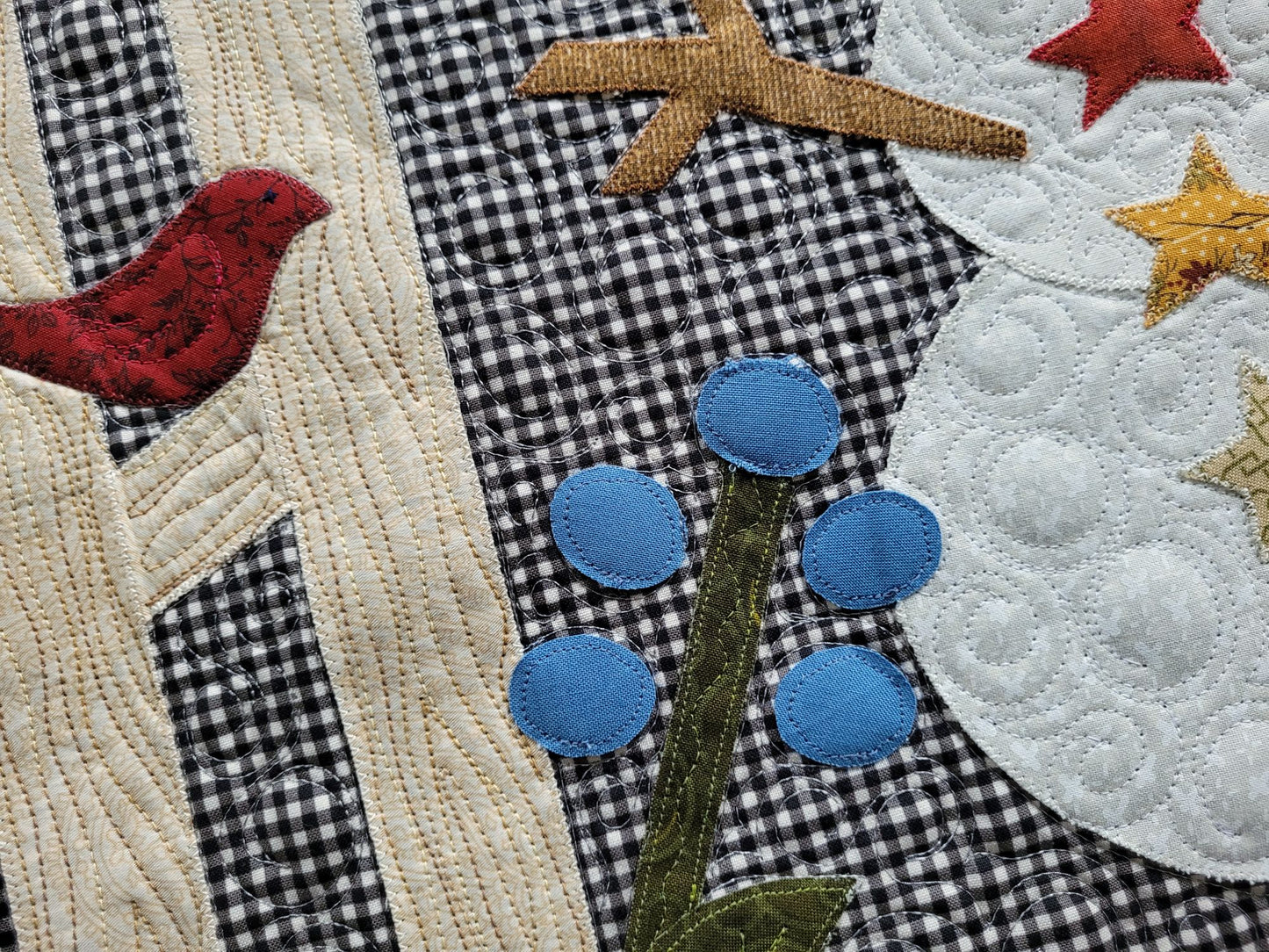 Showing close up stitching and applique detail on snowman, fence birds and flower.
