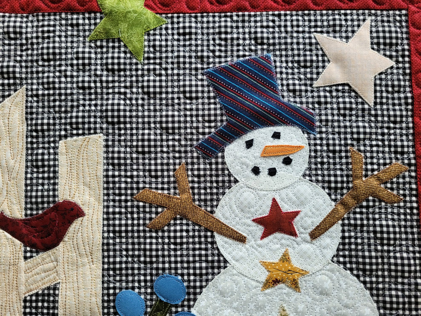 Showing close up detail and custom stitching of applique snowman on gingham background.