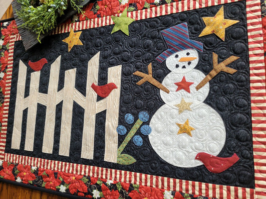 Applique snowman scene with rail fence, stars, birds on black quilted background and surrounded by red Christmas poinsettia border.
