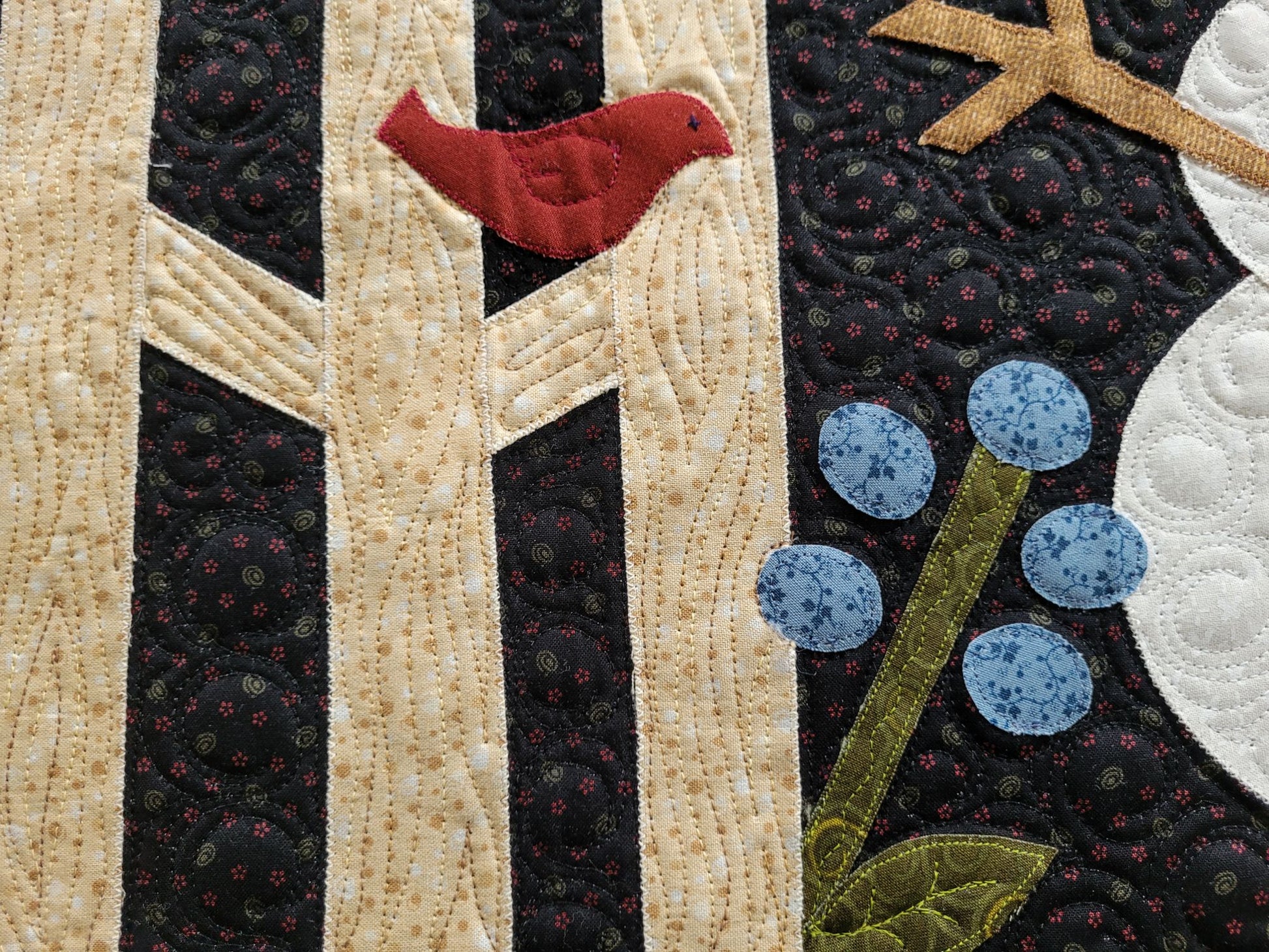 Showing close up of rail fence detail with wood grain stitching. A red bird is on the fence and a blue flower beside it.