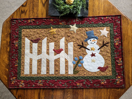 Rustic traditional colours are used in this applique snowman scene with rail fence, red birds and stars. Beige background, with a forest green border and then surrounded by a red candy cane print border in dark country red.