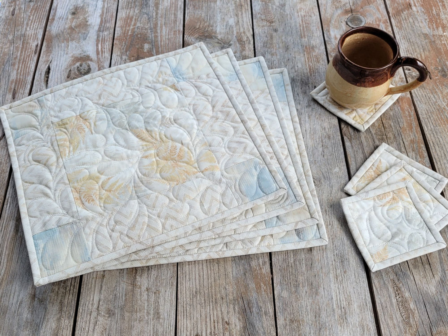 four neutral quilted placemats with matching coasters