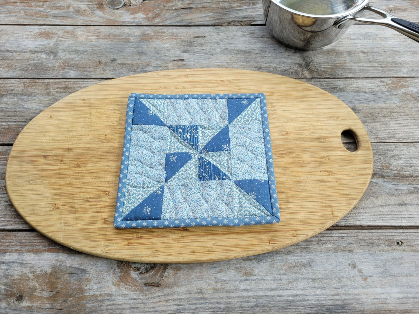 quilted hot mat in steel blue fabric with pinwheel patchwork design