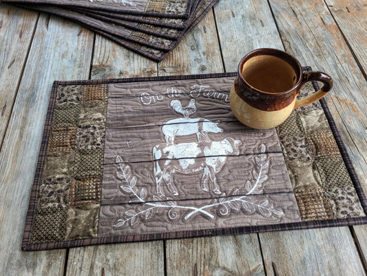 Quilted farm placemat with mug on wooden surface