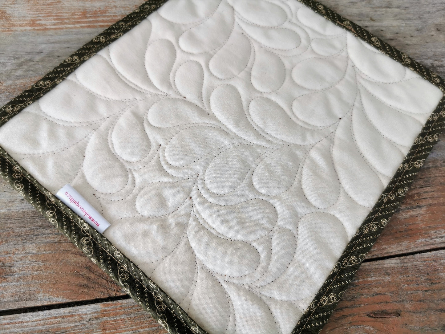 showing back of mini quilt with mommabearsquilts.ca tag. Feather quilting texture very visible.