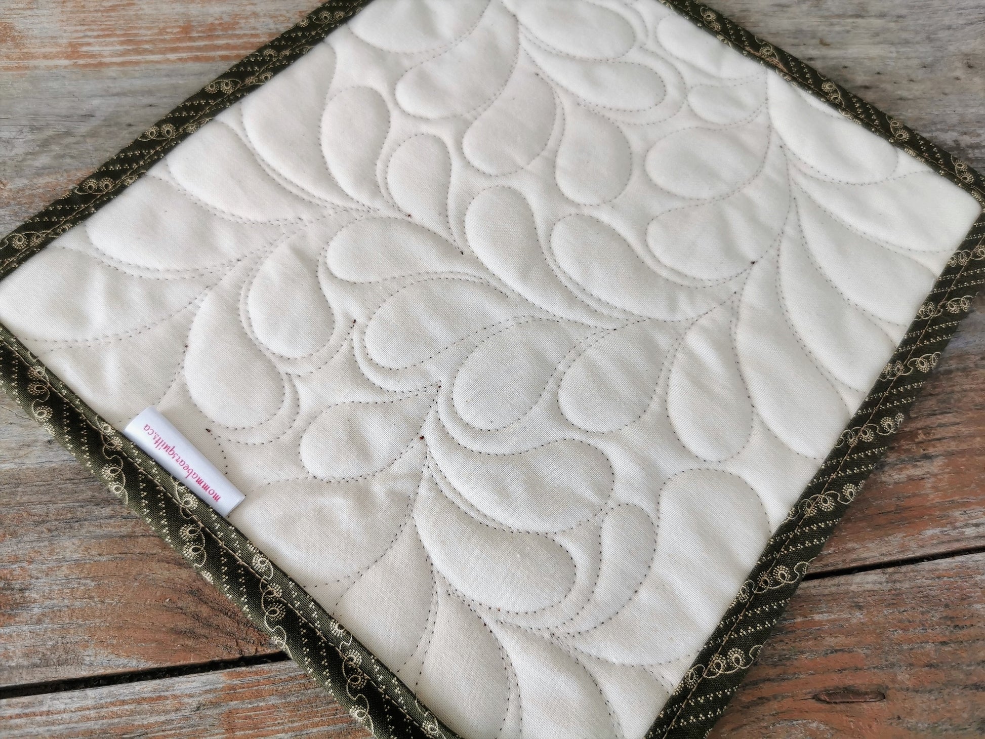 showing back of mini quilt with mommabearsquilts.ca tag. Feather quilting texture very visible.