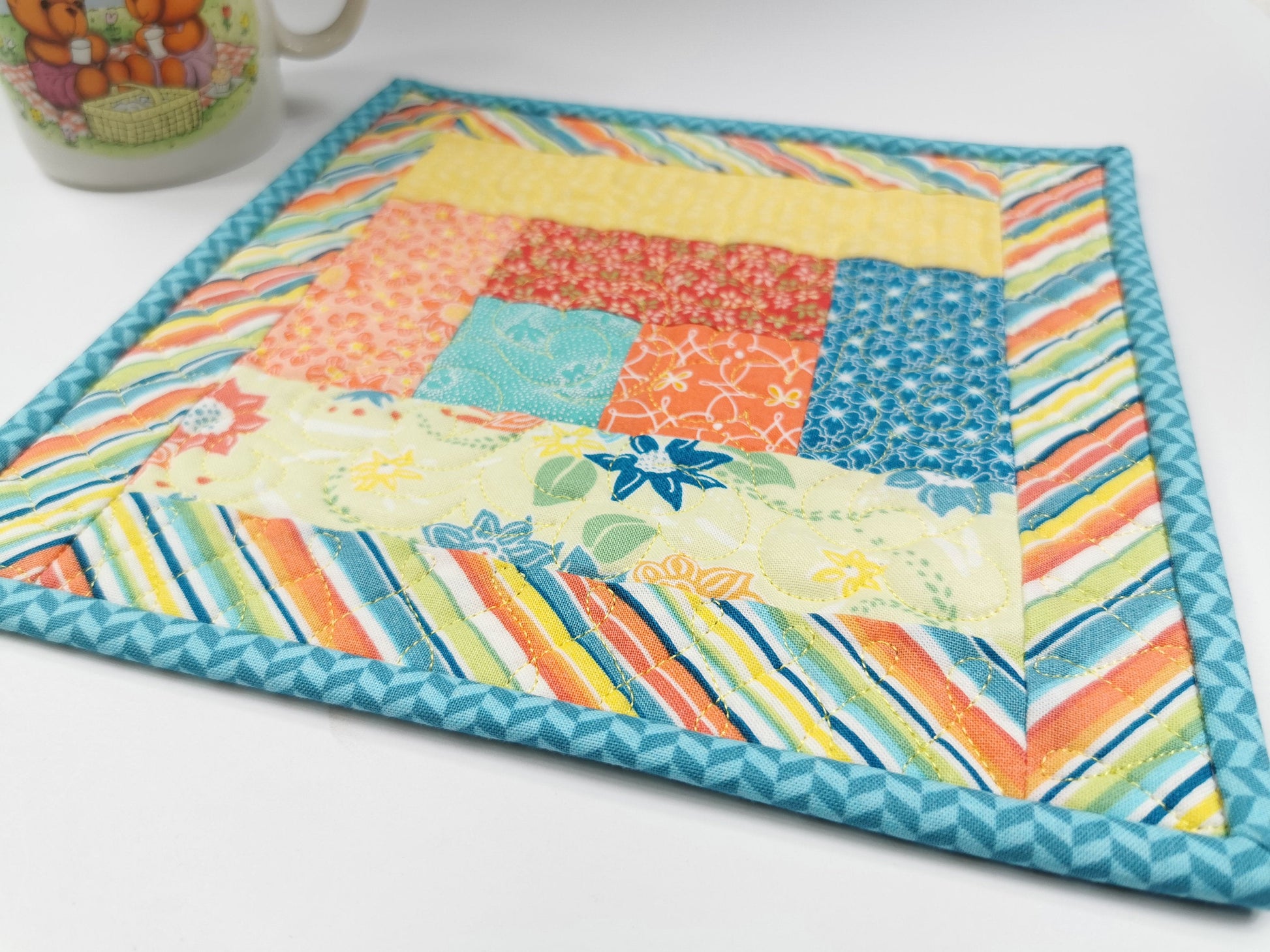 angle view of quilted mug rug with coffee mug in background