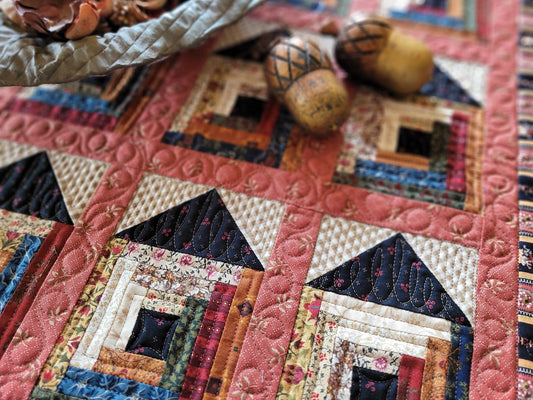 Quilt with house pattern featuring various colors and textures