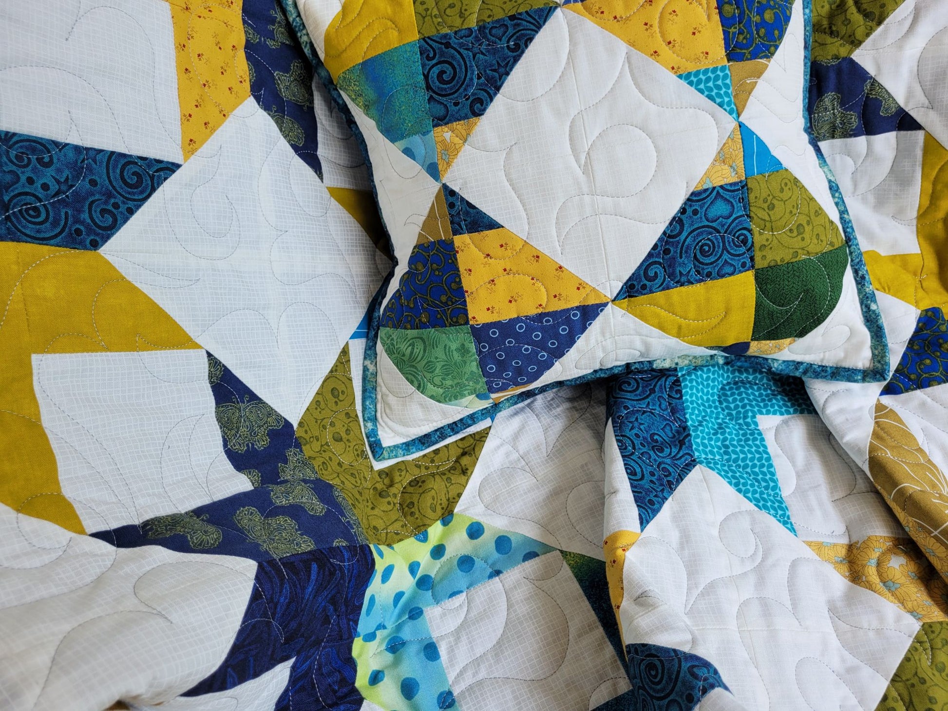 Close up detail of quilted throw blanket and pillow. 
