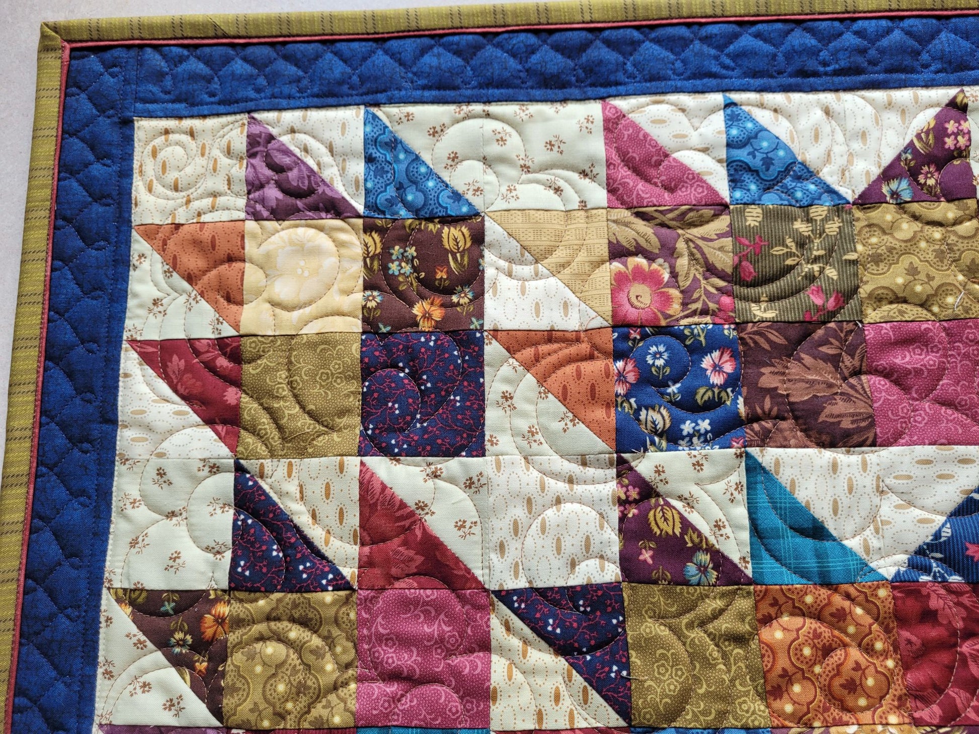 Quilt with patchwork design featuring various colours, border and flanged binding. 