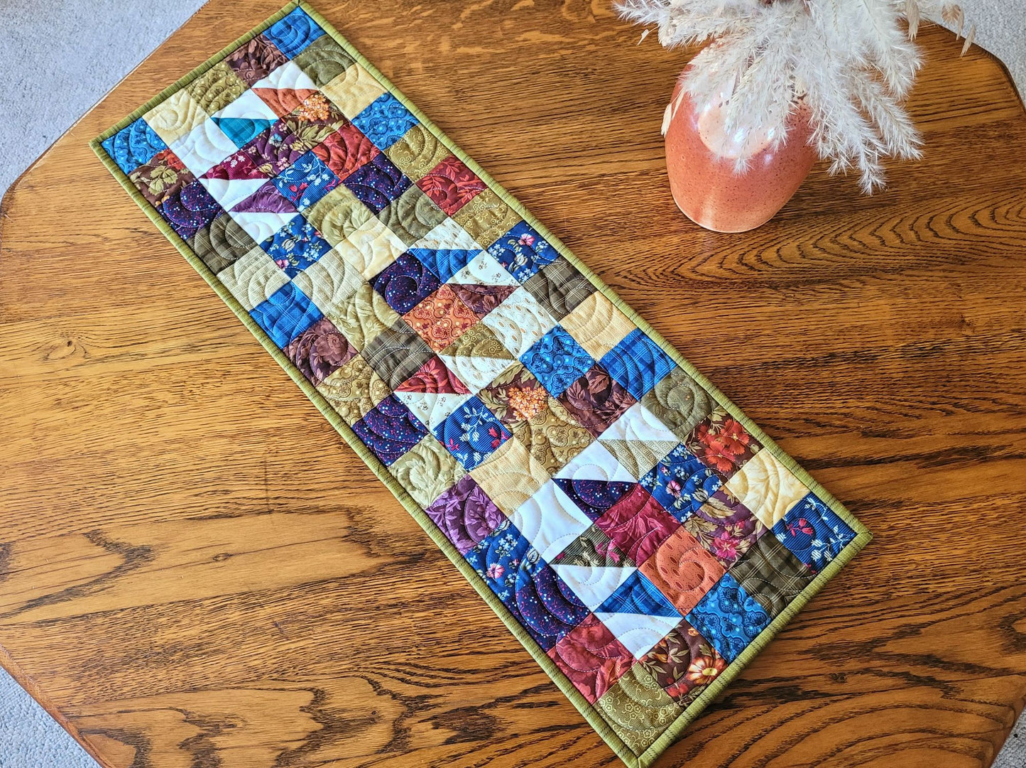 Quilted table runner with colourful patchwork design on a wooden surface