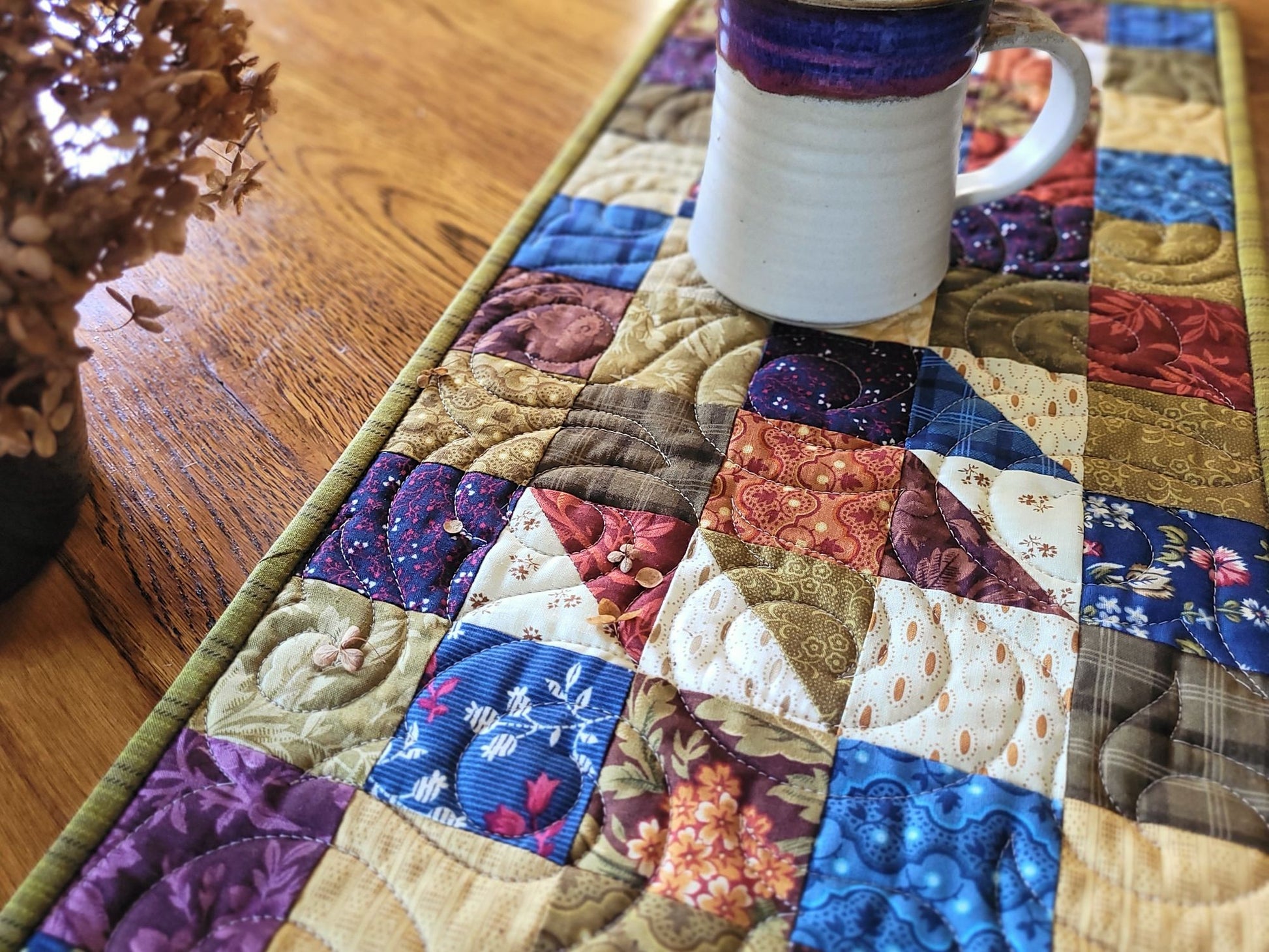 Quilted table runner with a mug on a wooden surface