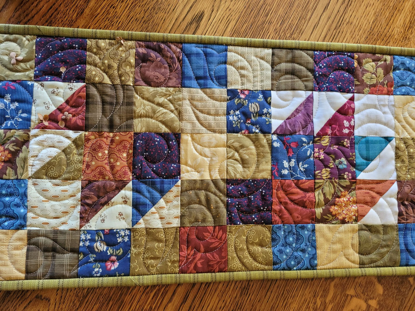 Quilted patchwork table runner on a wooden surface
