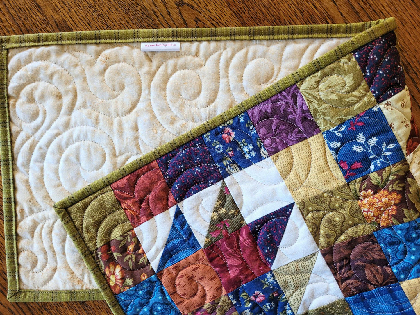 Quilted patchwork runner folded to show the back, on a wooden surface