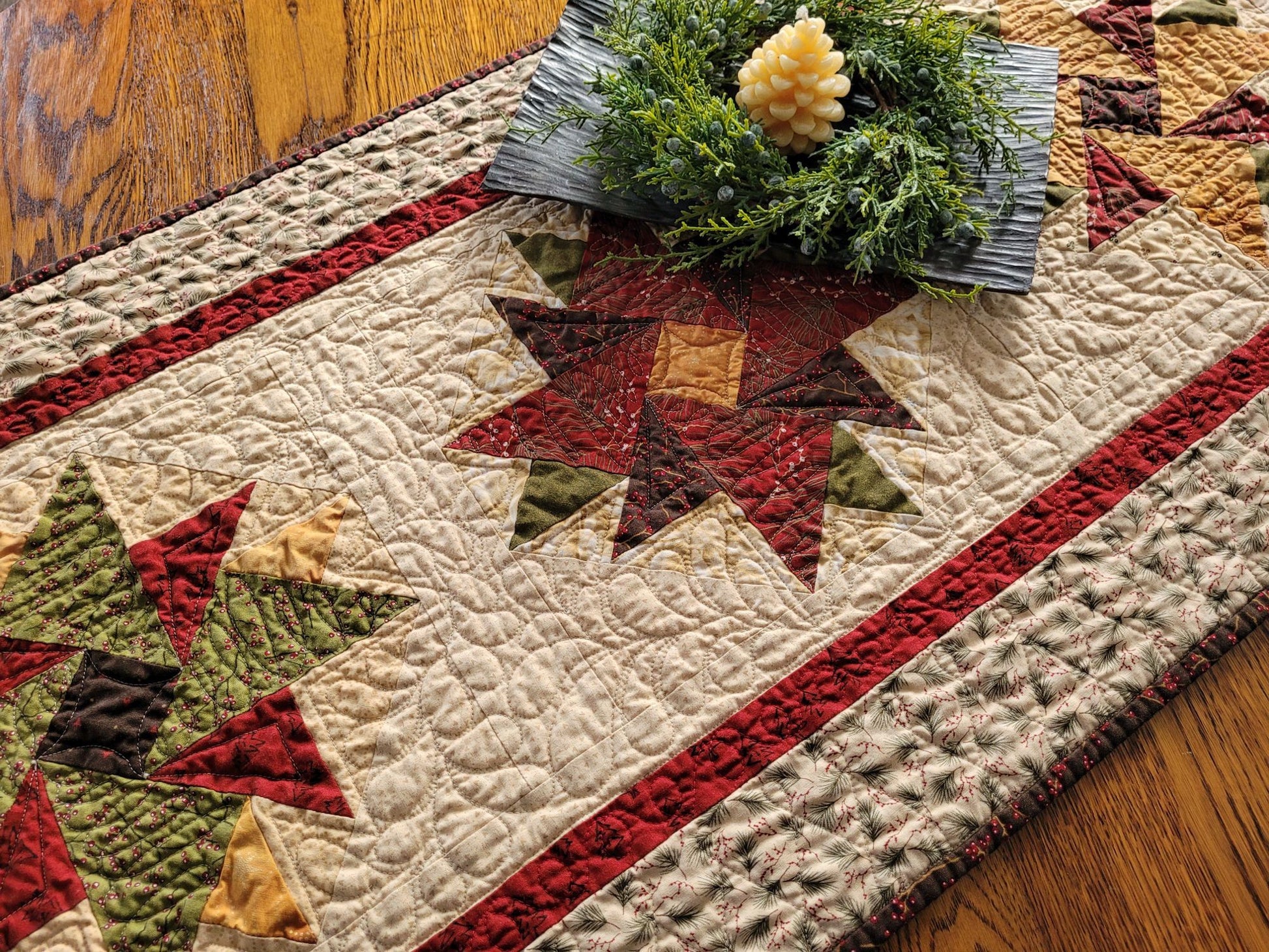Quilted table runner with star patterns on a wooden surface with a candle