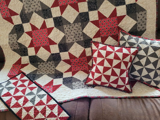 Quilt with geometric star pattern and matching pillows on a couch