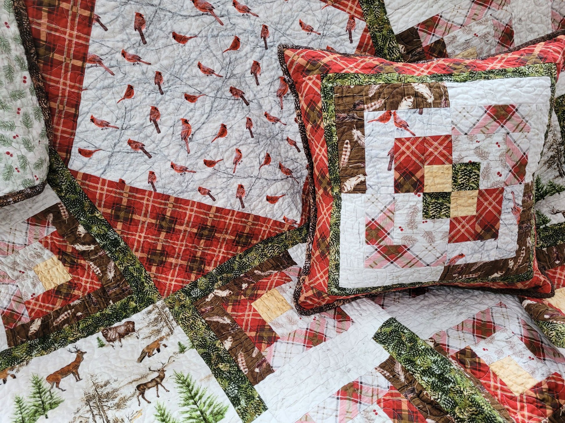 Quilted pillow and throw blanket with winter-themed patterns including birds, deer, and plaid.