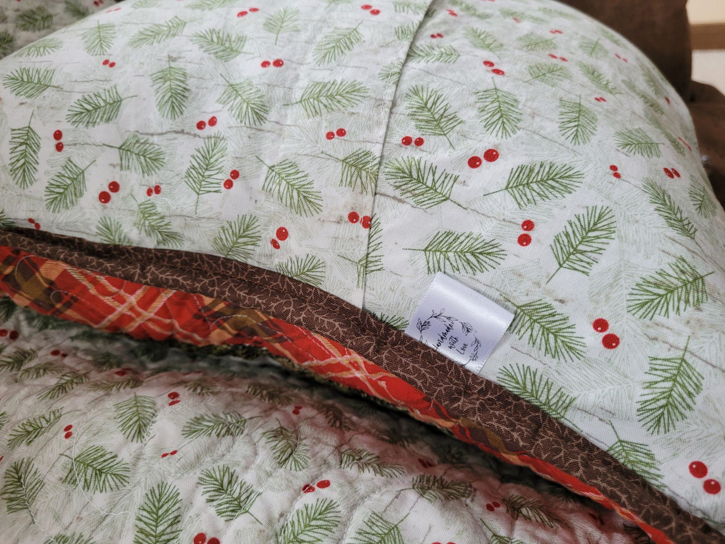Overlapping pillow back with pine tree pattern and red berries on a white background