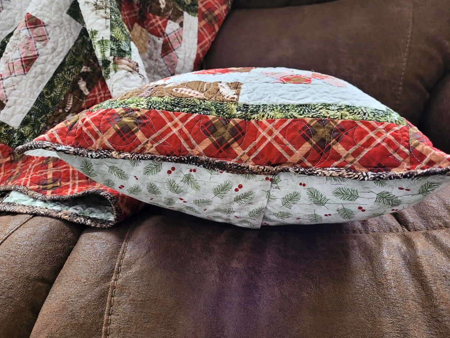 Quilted pillow with plaid pattern on a brown sofa, side view