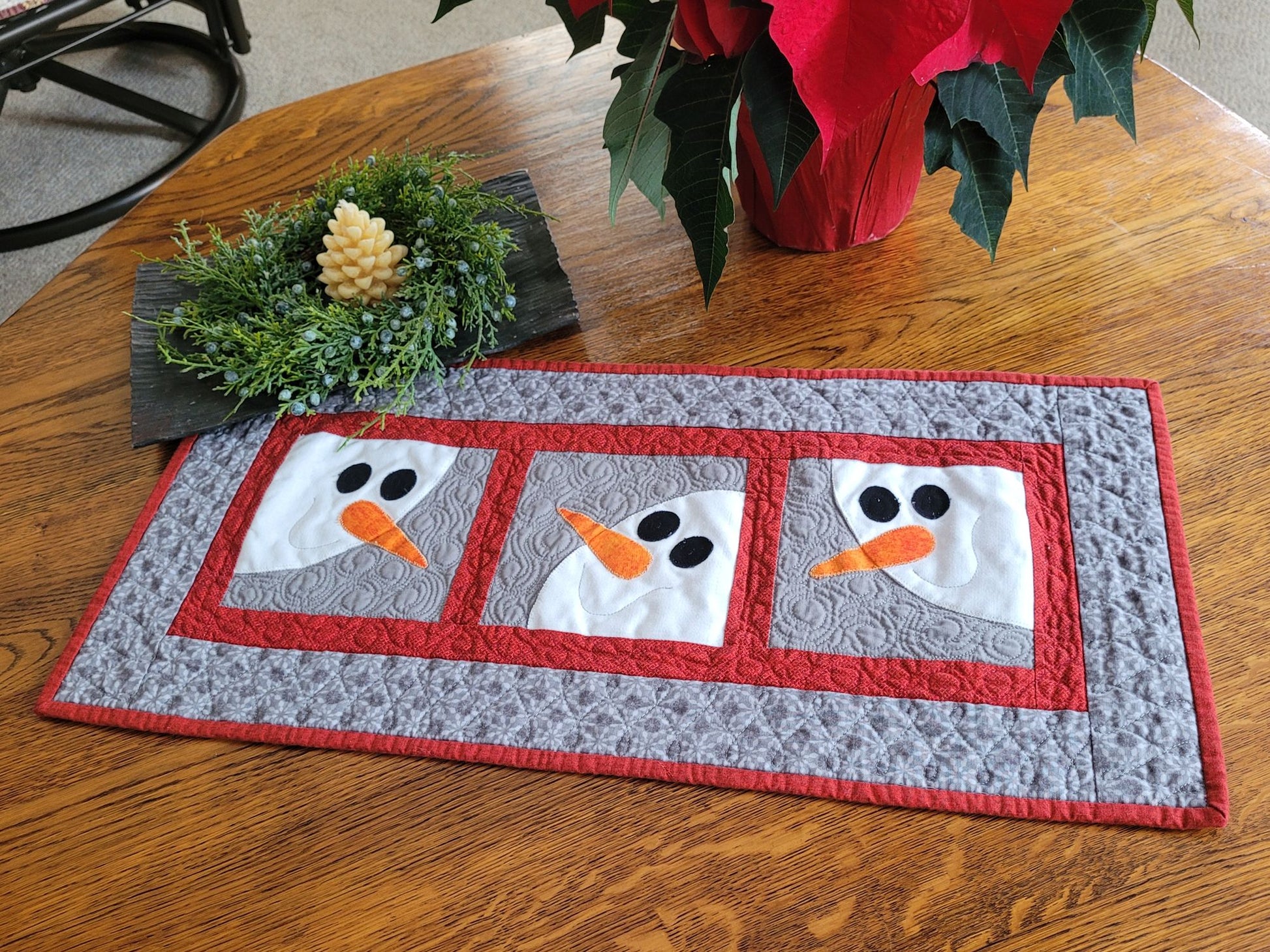 Quilted table runner with snowman design on a wooden table