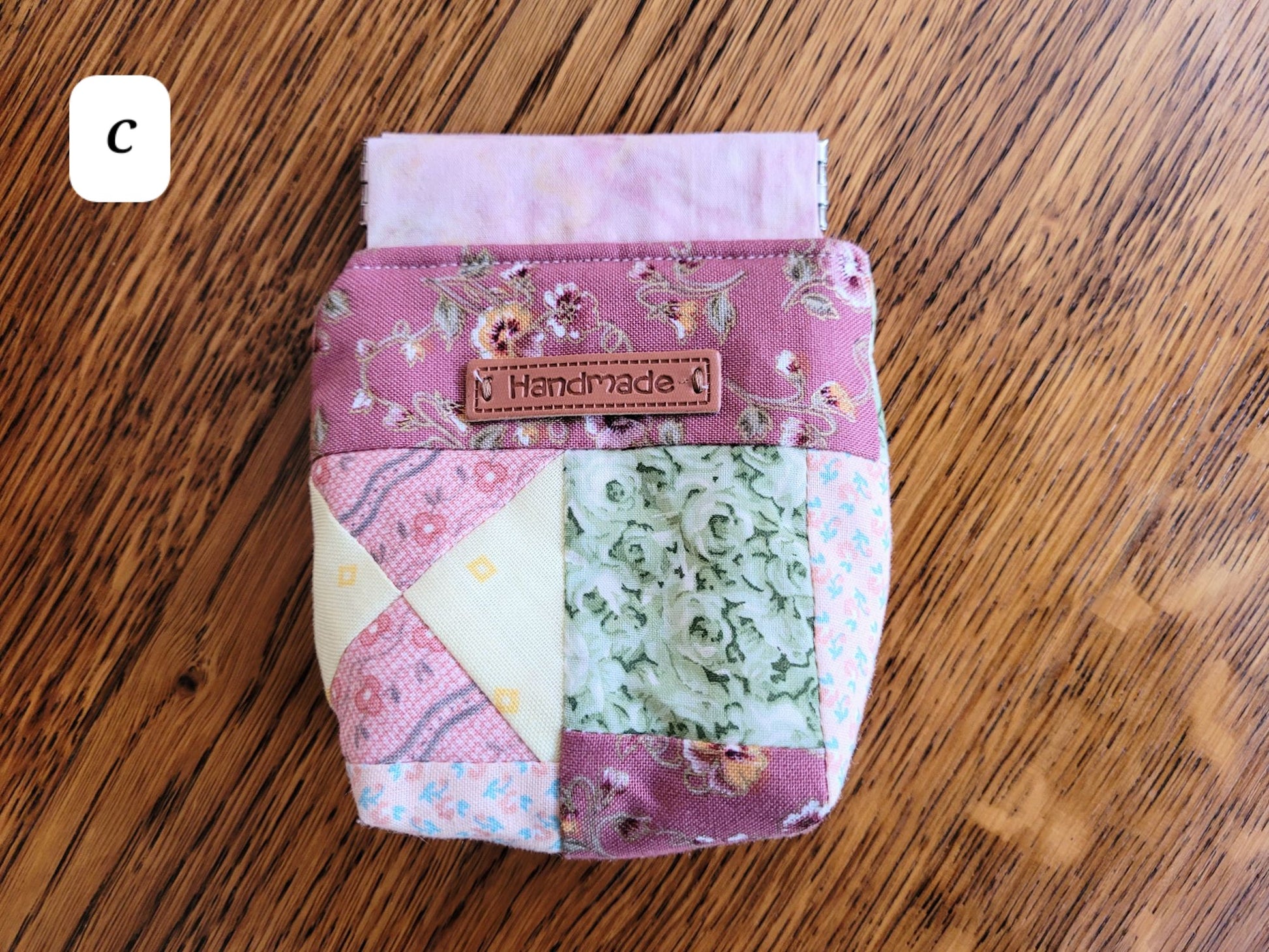 Handmade fabric pouch C with a 'Handmade' label on a wooden surface