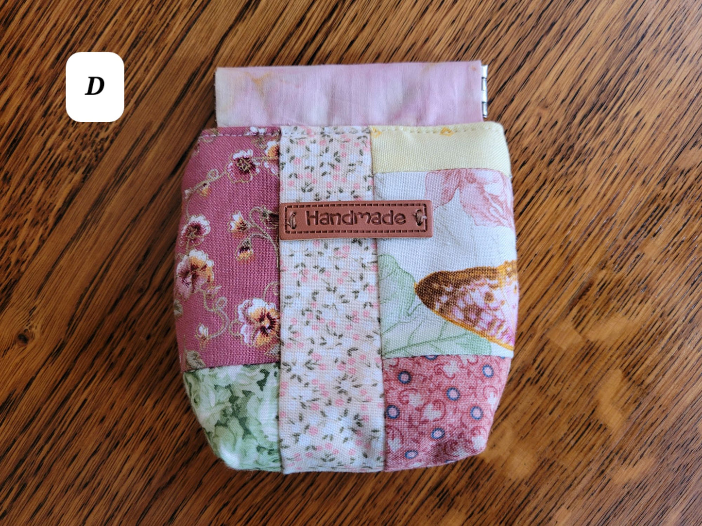Patchwork fabric pouch D with 'Handmade' label on a wooden surface
