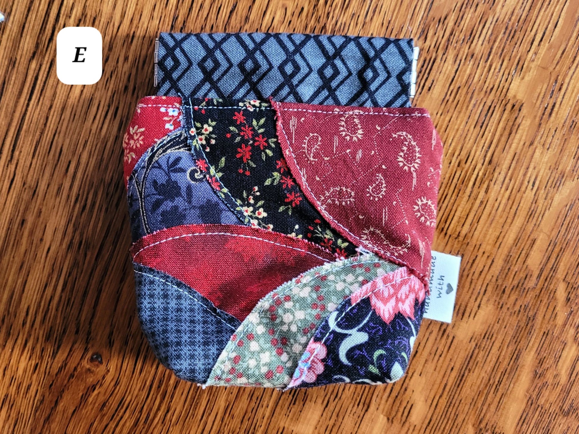Patchwork fabric spring pouch E on a wooden surface with a visible brand tag.