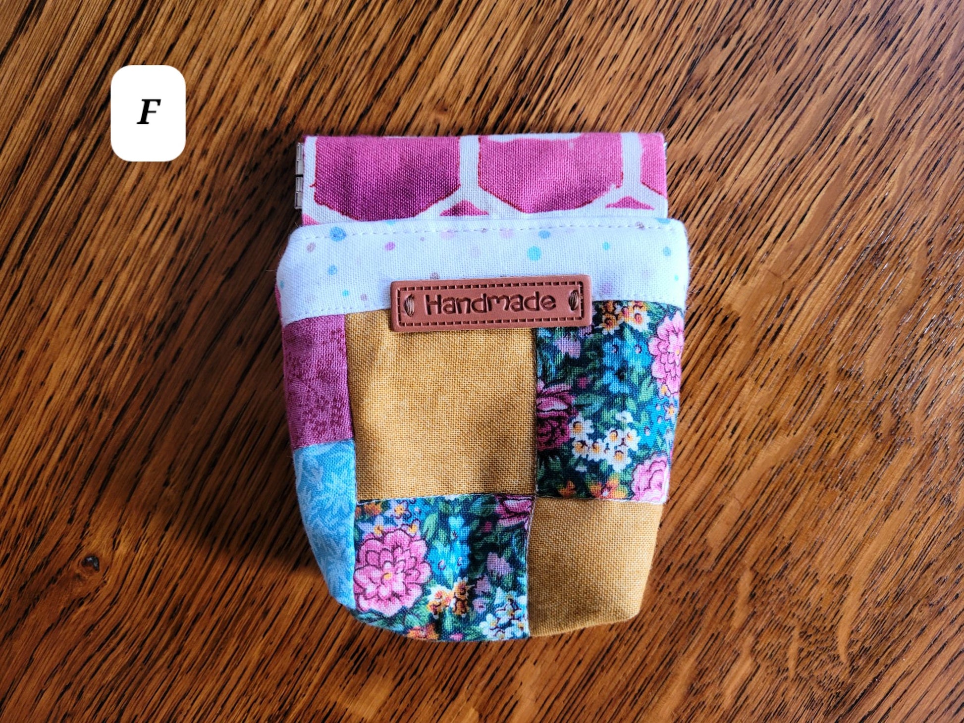 Colourful patchwork pouch F with 'Handmade' label on a wooden surface