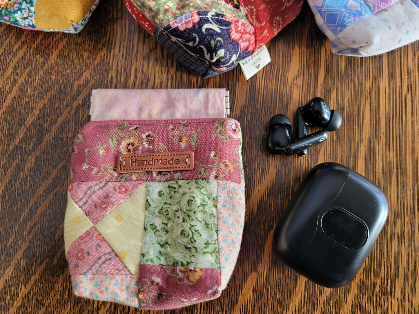 Handmade fabric ear bud pouch with floral pattern on a wooden surface