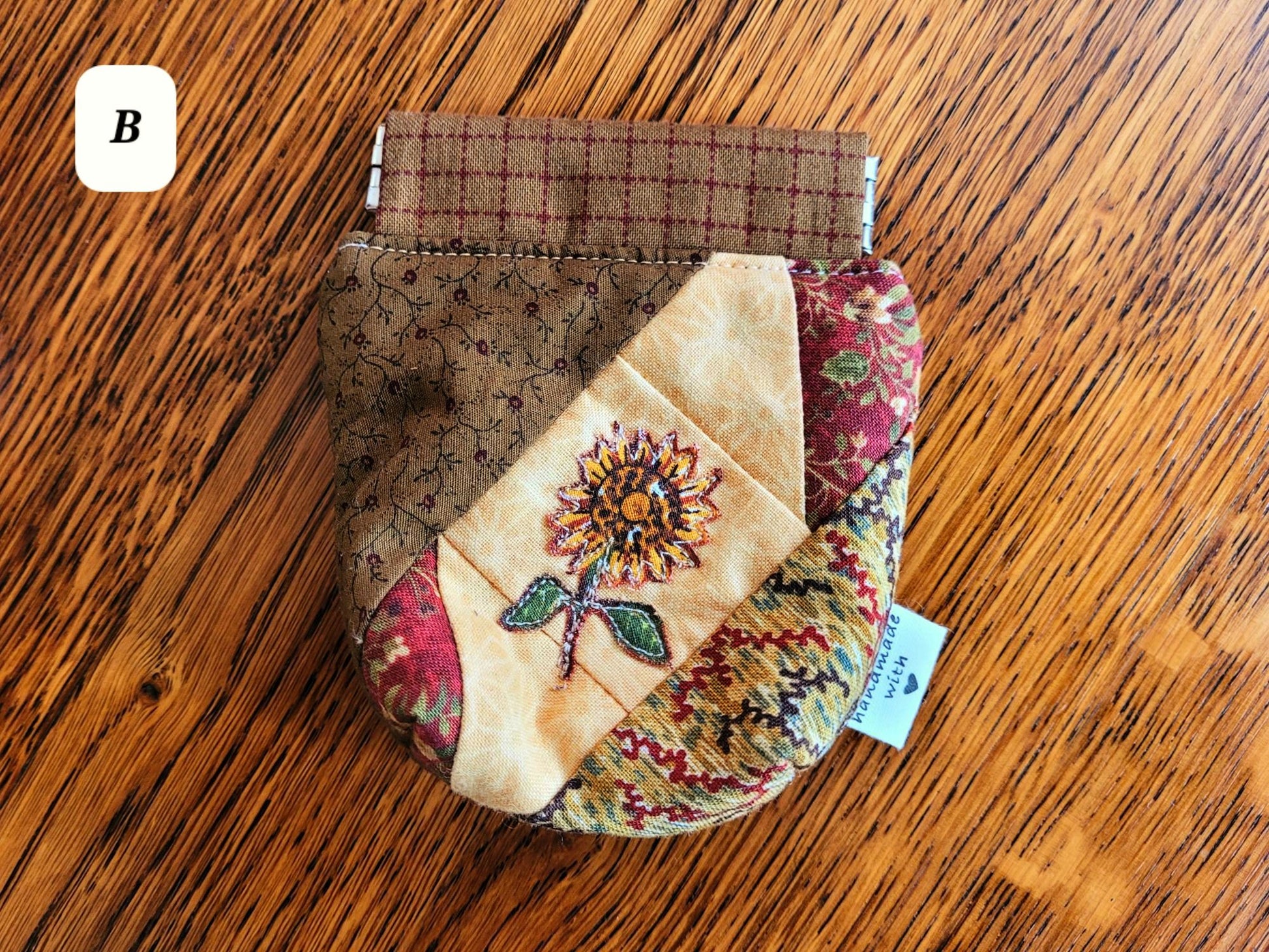 Patchwork spring snap pouch with floral embroidery on a wooden surface