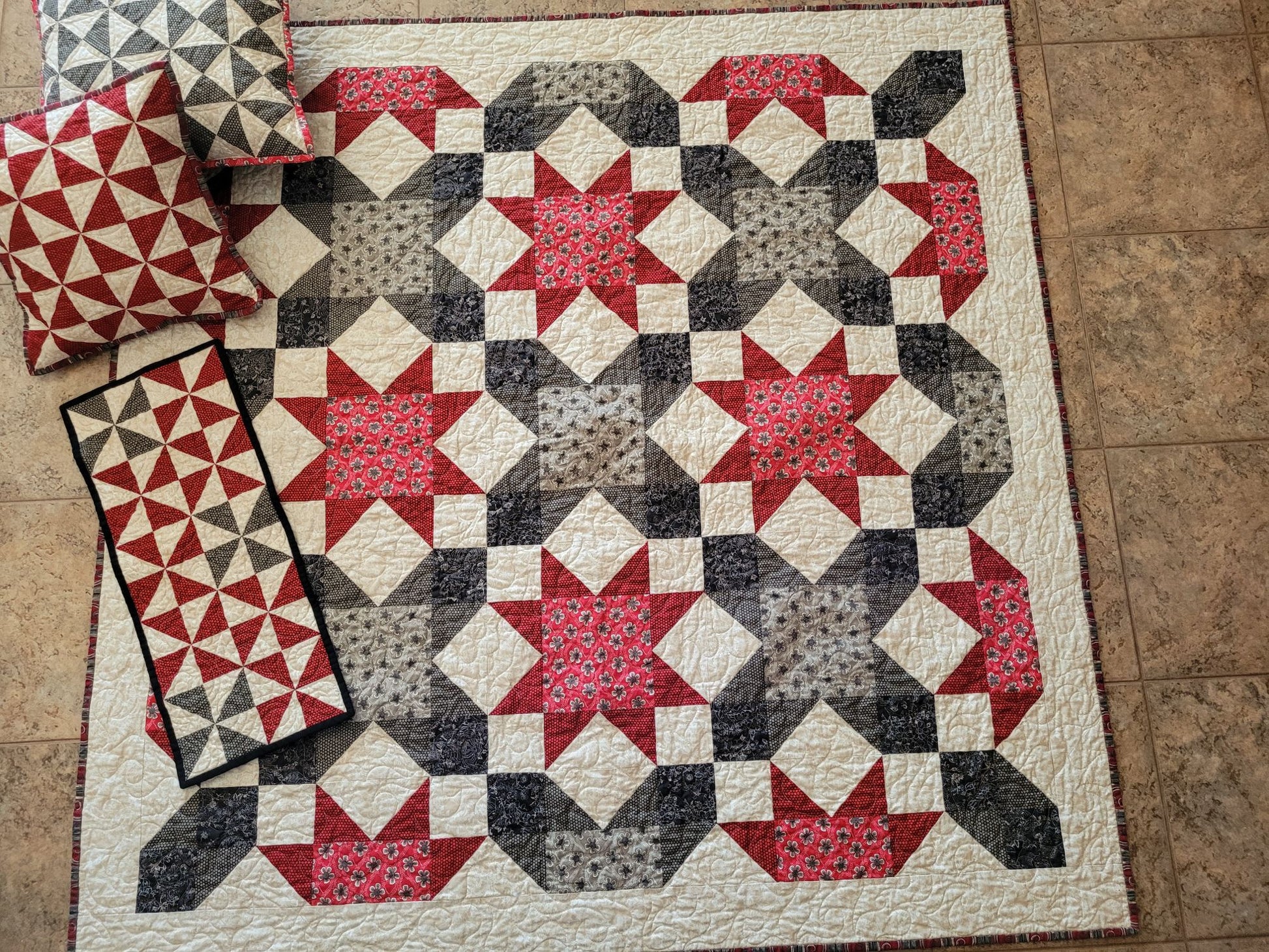 Quilt with star pattern on a tiled floor, with matching pillows and table runner