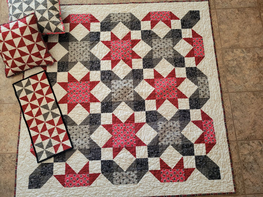 Quilt with star pattern on a tiled floor, with matching pillows and table runner