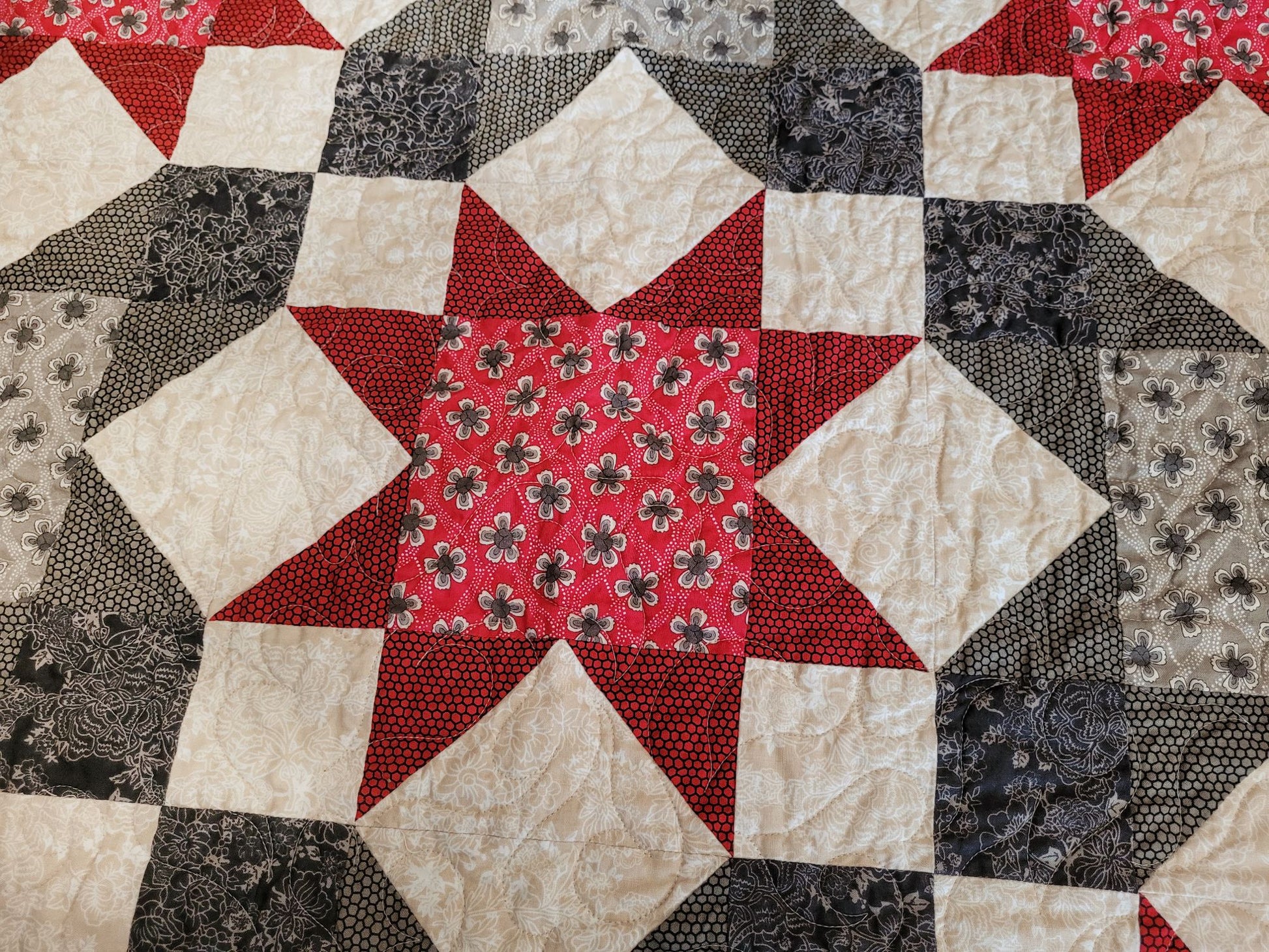 Close-up of a patchwork quilt with star pattern featuring red, black, and beige colours.